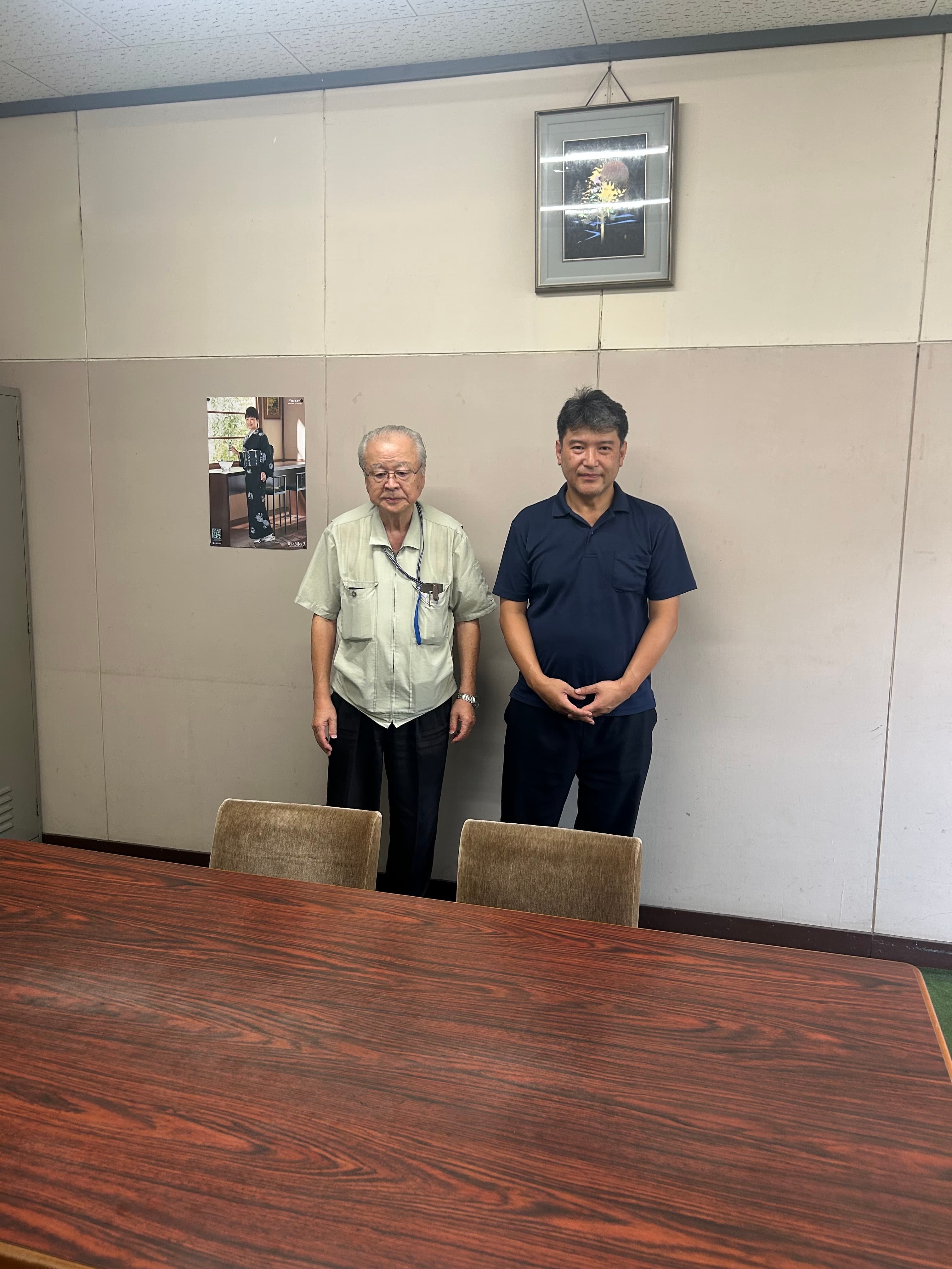 工場の会議室に並んで立つ二人