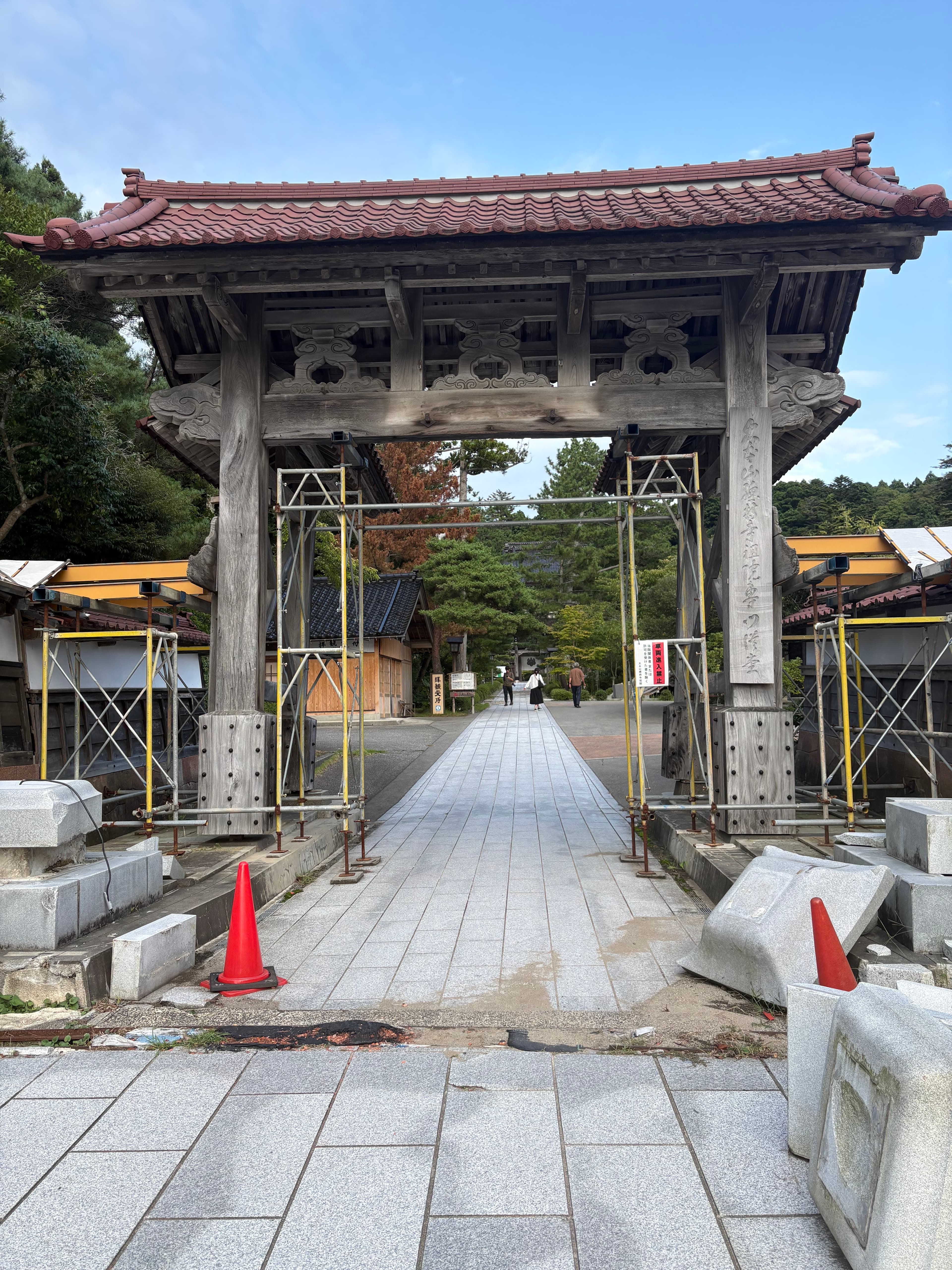 足場や鉄骨が組まれ、足元に倒れた石材が残る總持寺祖院の門
